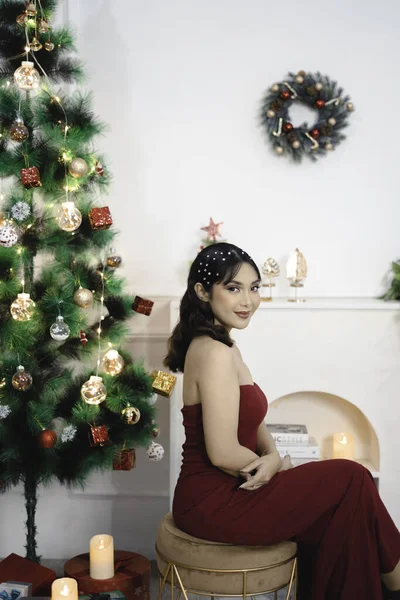かなり若い女の子の肖像居心地の良い座って 笑顔装飾されたクリスマスのリビングルームで赤いガウンを身に着けて室内 — ストック写真