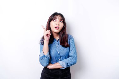 A thoughtful young woman dressed in blue shirt while looking aside, isolated by white background
