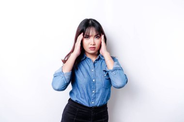 A portrait of an Asian woman wearing a blue shirt isolated by white background looks depressed