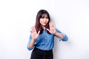 Genç Asyalı bir kadın beyaz arka planda izole edilmiş, depresif görünüyor, yüzü parmaklarla kaplı korkmuş ve gergin..