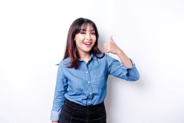 Mavi tişört giyen heyecanlı Asyalı kadın beyaz arkaplan tarafından izole edilmiş, el hareketleriyle onaylıyor.