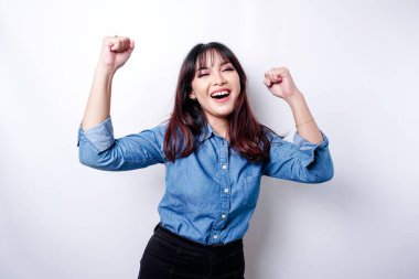 A young Asian woman with a happy successful expression wearing blue shirt isolated by white background