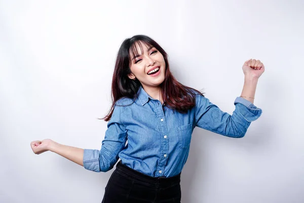 A young Asian woman with a happy successful expression wearing blue shirt isolated by white background
