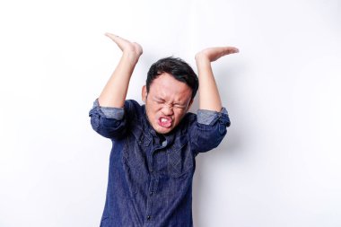 Shocked Asian man wearing blue shirt pointing at the copy space on top of him, isolated by white background