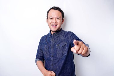 Young Asian man wearing blue shirt standing over isolated white background pointing fingers to camera with happy face. Good energy and vibes.