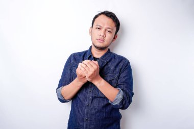 Sakin, yakışıklı Asyalı adam gözleri kapalı dua ediyor. El ele tutuşup meditasyon yapan ciddi, barışçıl genç bir adam. İnanç kavramı