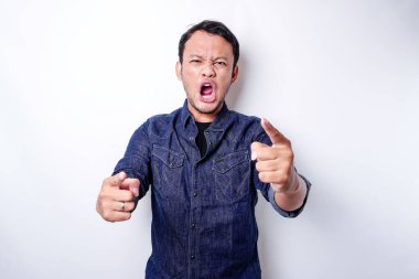 The angry and mad face of Asian man in blue shirt isolated white background.