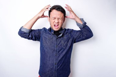 The angry and mad face of Asian man in blue shirt isolated white background.
