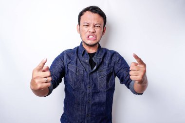 The angry and mad face of Asian man in blue shirt isolated white background.