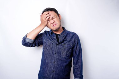 A portrait of an Asian man wearing a blue shirt isolated by white background looks depressed