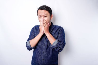 A portrait of an Asian man wearing a blue shirt isolated by white background looks depressed