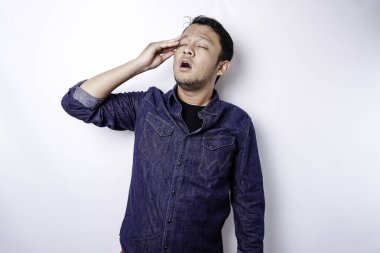 A portrait of an Asian man wearing a blue shirt isolated by white background looks depressed