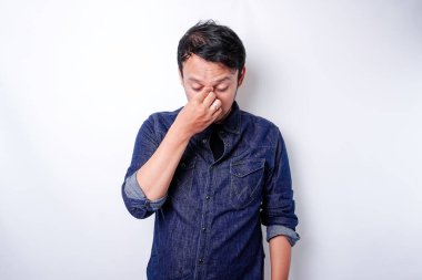 A portrait of an Asian man wearing a blue shirt isolated by white background looks depressed