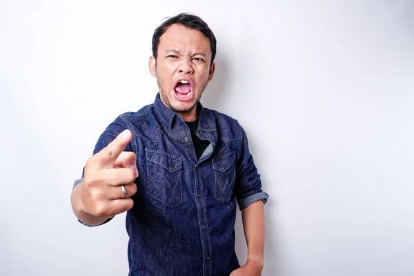 The angry and mad face of Asian man in blue shirt isolated white background.