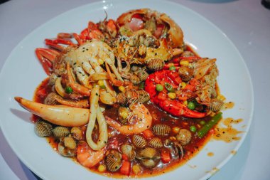 A photo of a plate of seafood contains of crabs, shrimps, squid and clams
