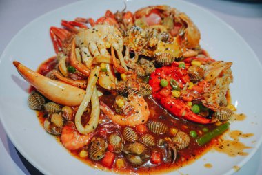 A photo of a plate of seafood contains of crabs, shrimps, squid and clams