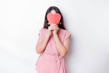 Asian woman holding a red paper heart shape covering her face. Valentine concept