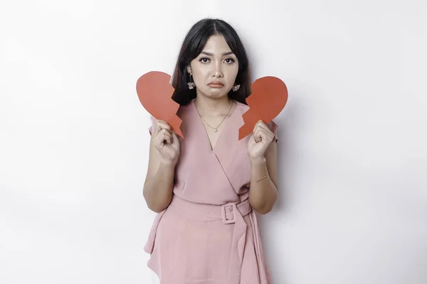 Beautiful young Asian woman expressed her sadness while holding broken heart isolated on white background
