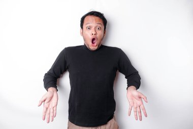 Shocked Asian man wearing black shirt, pointing at the copy space below him, isolated by white background