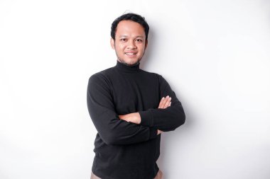 An Asian young confident man posing with crossed arm against a white background.