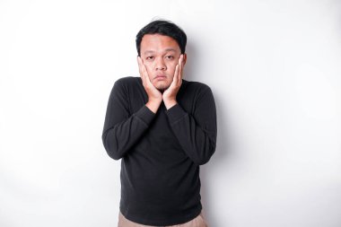 A portrait of an Asian man wearing a black shirt isolated by white background looks depressed