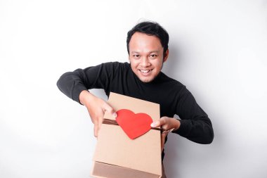Beautiful young Asian man wearing black shirt holding gift box red heart, Valentine's Day concept.