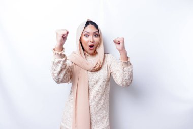 Mutlu bir ifadeyle genç bir Asyalı Müslüman kadın beyaz arka planla izole edilmiş tesettür takıyor.