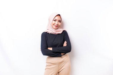 Portrait of a confident smiling Asian Muslim woman wearing hijab standing with arms folded and looking at the camera isolated over white background