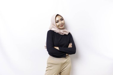 Portrait of a confident smiling Asian Muslim woman wearing hijab standing with arms folded and looking at the camera isolated over white background
