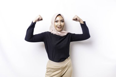Heyecanlı Asyalı Müslüman kadın tesettüre girmiş kollarını ve kaslarını gururla kaldırarak güçlü bir hareket sergiliyor.