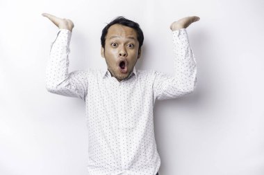 Shocked Asian man wearing white shirt pointing at the copy space on top of him, isolated by white background