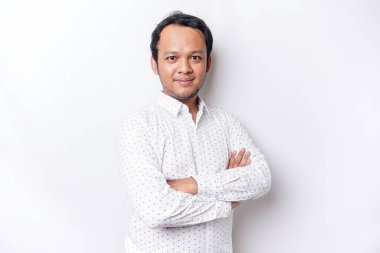 An Asian young confident man posing with crossed arm against a white background.