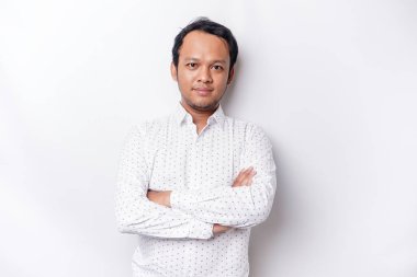 An Asian young confident man posing with crossed arm against a white background.