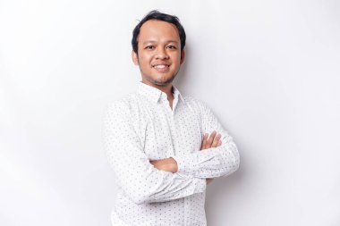 An Asian young confident man posing with crossed arm against a white background.