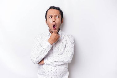 Shocked Asian man with his mouth wide open wearing white shirt, isolated by a white background