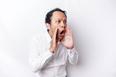 Young handsome man wearing a white shirt shouting and screaming loud with a hand on his mouth. communication concept.
