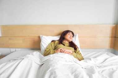 Genç ve güzel Asyalı kadın yatağında uyuyor ve sabahları dinleniyor.
