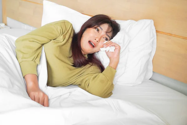 悲しいアジア系の若い女性がベッドの上に横になって泣いている — ストック写真