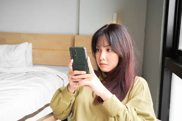 아시아의한 여성은 침실에 스마트폰을 진지하게 주의를 기울이고 — 스톡 사진