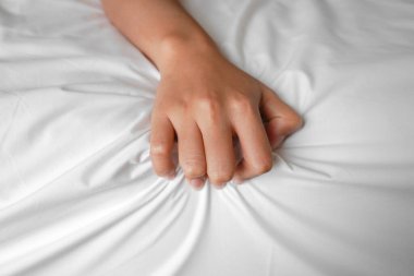 Bir erkekle kadının ellerinin yatakta sevişirken çekilmiş bir fotoğrafı. Sevişmek.