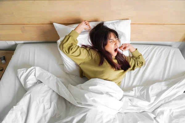 어여쁜 아시아 여성밝은 침실에 그녀의 침대에 스트레칭 — 스톡 사진