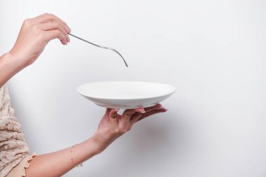 Close-up, holding a white plate and spoon, isolated on a white background. clipart