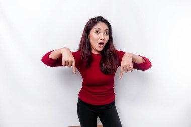 Kırmızı giyinmiş şok olmuş Asyalı kadın, altındaki fotokopi alanını işaret ediyor, beyaz arka planla izole edilmiş.