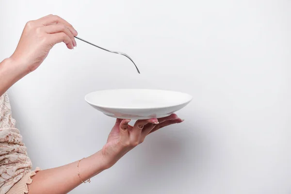 stock image Close-up, holding a white plate and spoon, isolated on a white background.