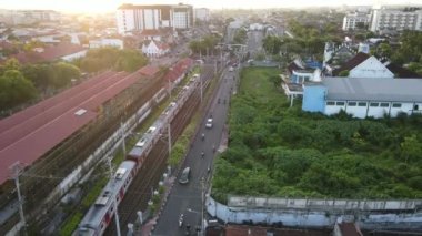 Yolcu treninin Tugu İstasyonu yakınlarındaki tren köprüsünü geçerken hava görüntüsü. Yogyakarta, Endonezya - Ocak 2023. 