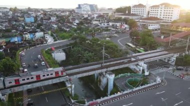Yolcu treninin Tugu İstasyonu yakınlarındaki tren köprüsünü geçerken hava görüntüsü. Yogyakarta, Endonezya - Ocak 2023. 