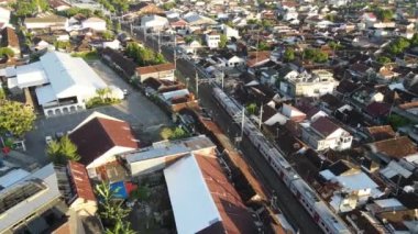 Yolcu treninin Tugu İstasyonu yakınlarındaki tren köprüsünü geçerken hava görüntüsü. Yogyakarta, Endonezya - Ocak 2023. 