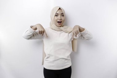 Aşağıdaki fotokopi alanını gösteren başörtüsü takan, beyaz arkaplan ile izole edilmiş, şok olmuş Asyalı Müslüman kadın.