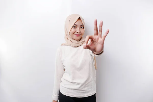 一位面带微笑的亚裔穆斯林妇女 在苍白的背景下做出了一个令人愉快的手势 — 图库照片