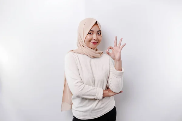 一位面带微笑的亚裔穆斯林妇女 在苍白的背景下做出了一个令人愉快的手势 — 图库照片